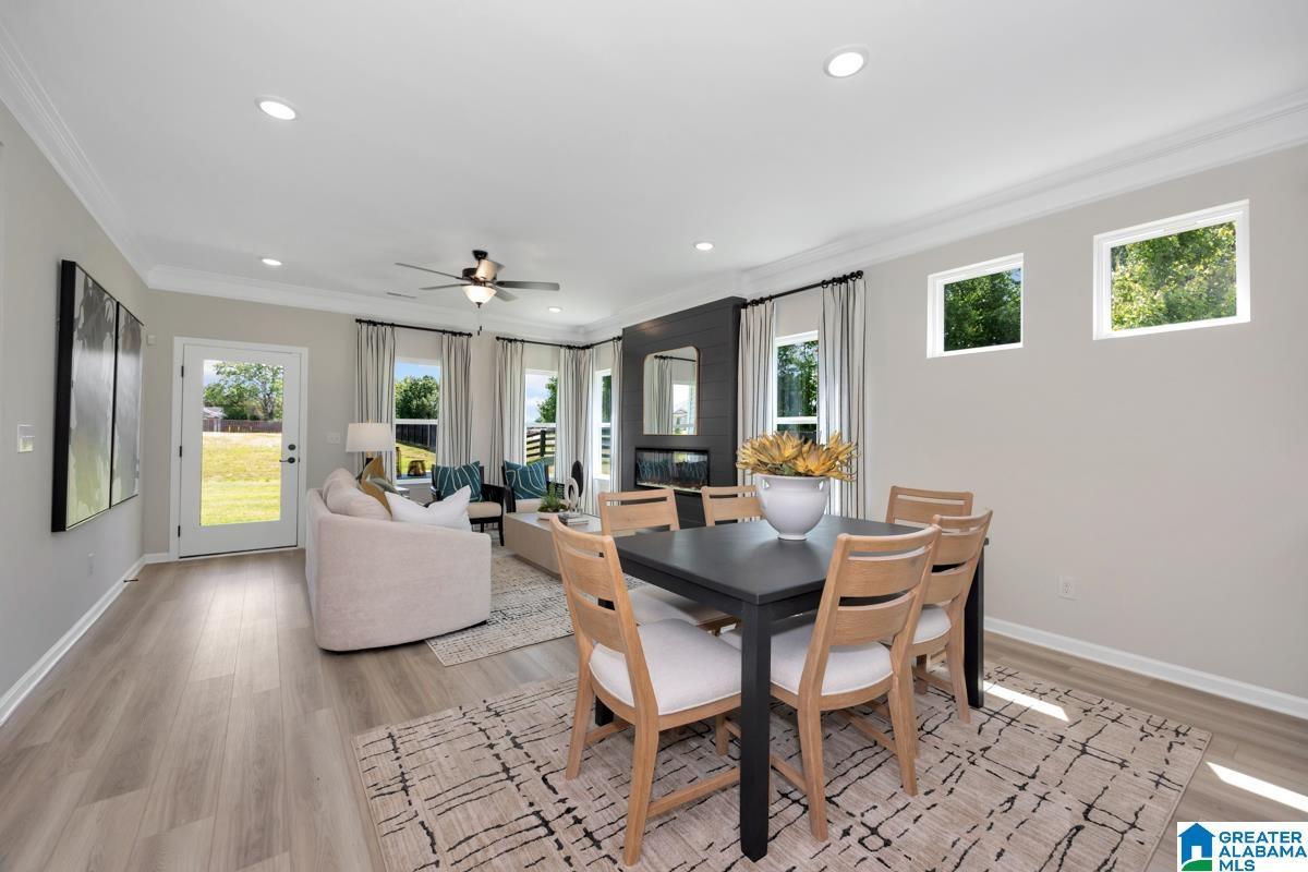 Open-concept living space featuring wood-finish flooring, recessed lighting, and crown molding