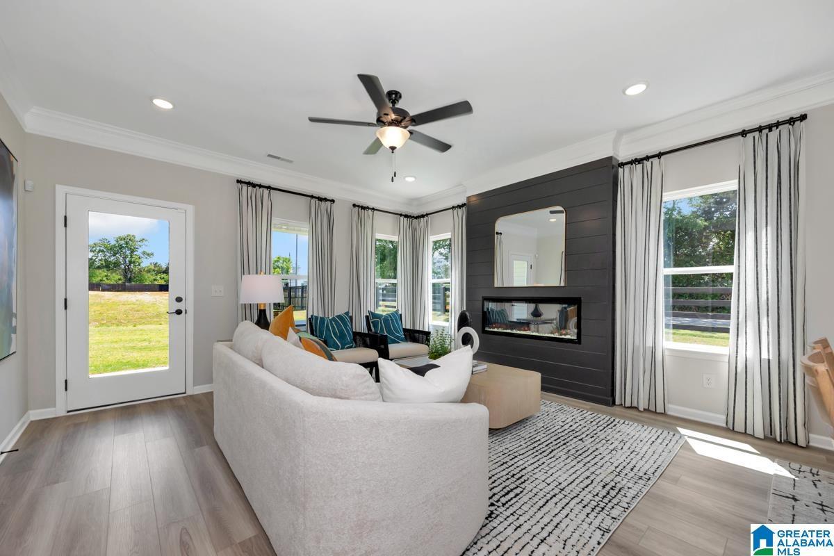 Wood-finish flooring throughout, recessed ceiling lighting, ceiling fan, and a built-in horizontal fireplace with a shiplap accent wall