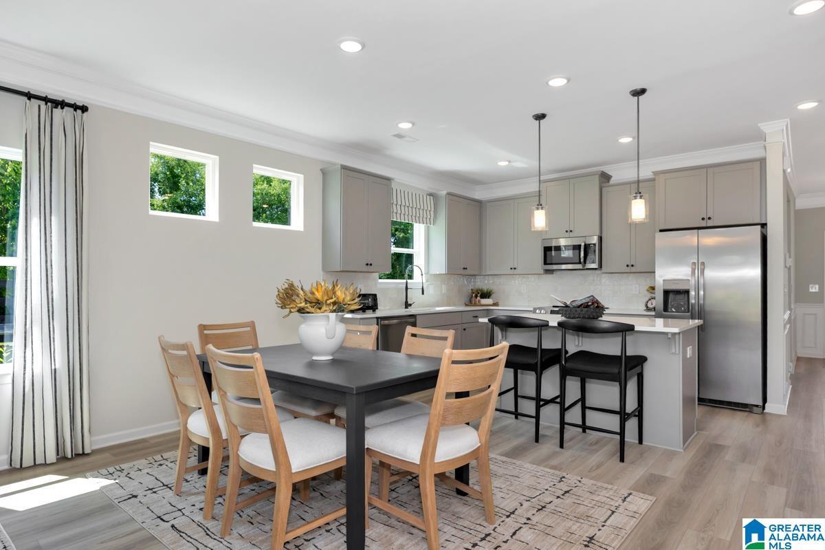 Kitchen featuring light gray cabinetry, stainless steel appliances, and a central island with counter seating