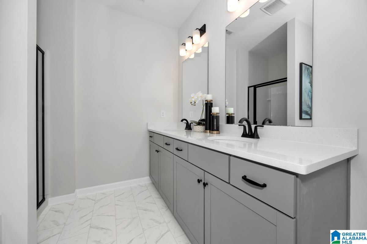 Dual vanities with white countertops, matte black hardware, and light gray cabinetry