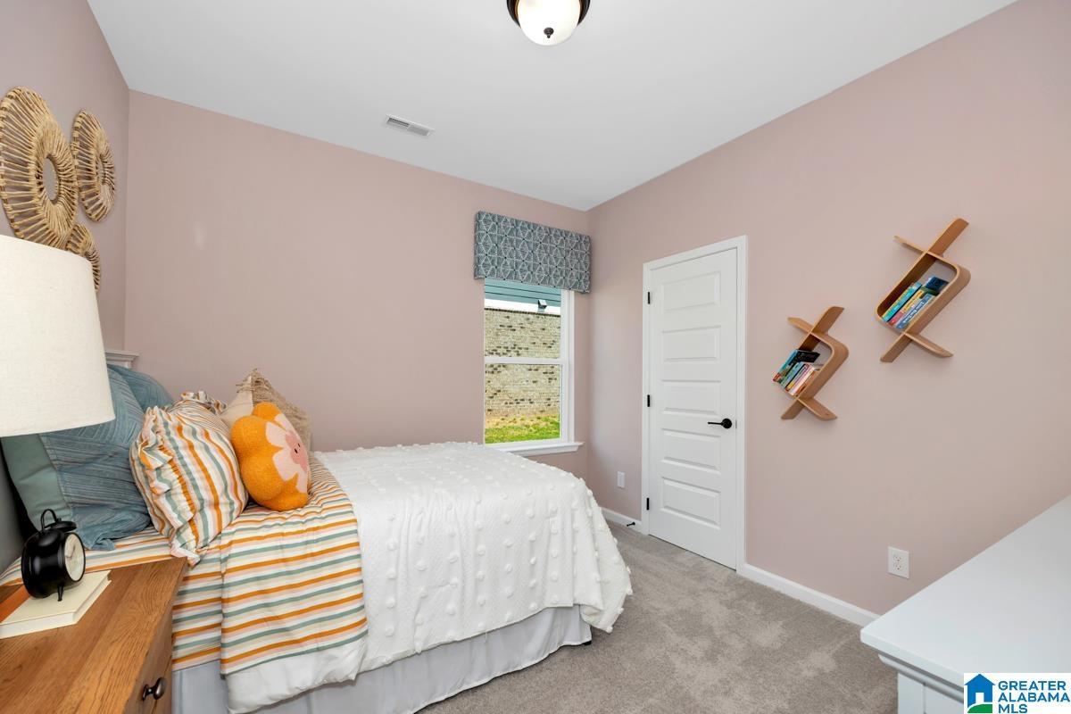 Recessed lighting, window with patterned valance, paneled interior door with dark hardware, built-in shelving, and light gray carpeting