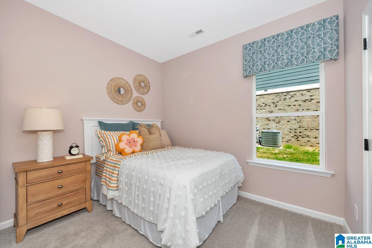 Soft pink walls complement the light gray carpet flooring