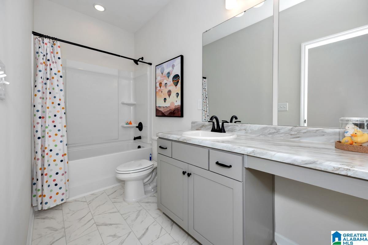 White tile flooring, white vanity with integrated sink, black faucet, large vanity mirror, and white bathtub with shower