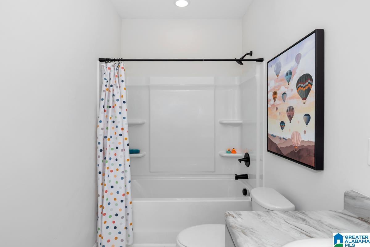 Tub and shower combination with matte black fixtures, integrated shelving, and a single recessed light