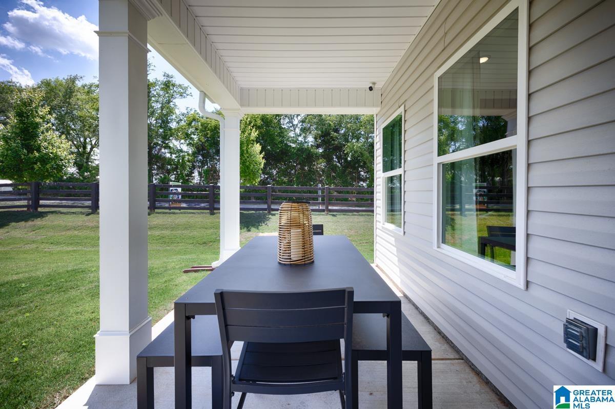 Covered patio with a concrete surface, white support columns, and light gray siding
