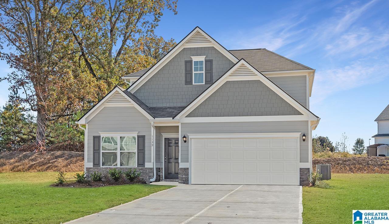 Gable roofline with architectural shingles, light gray siding, dark gray shake siding accents, black window shutters, and a two-car garage