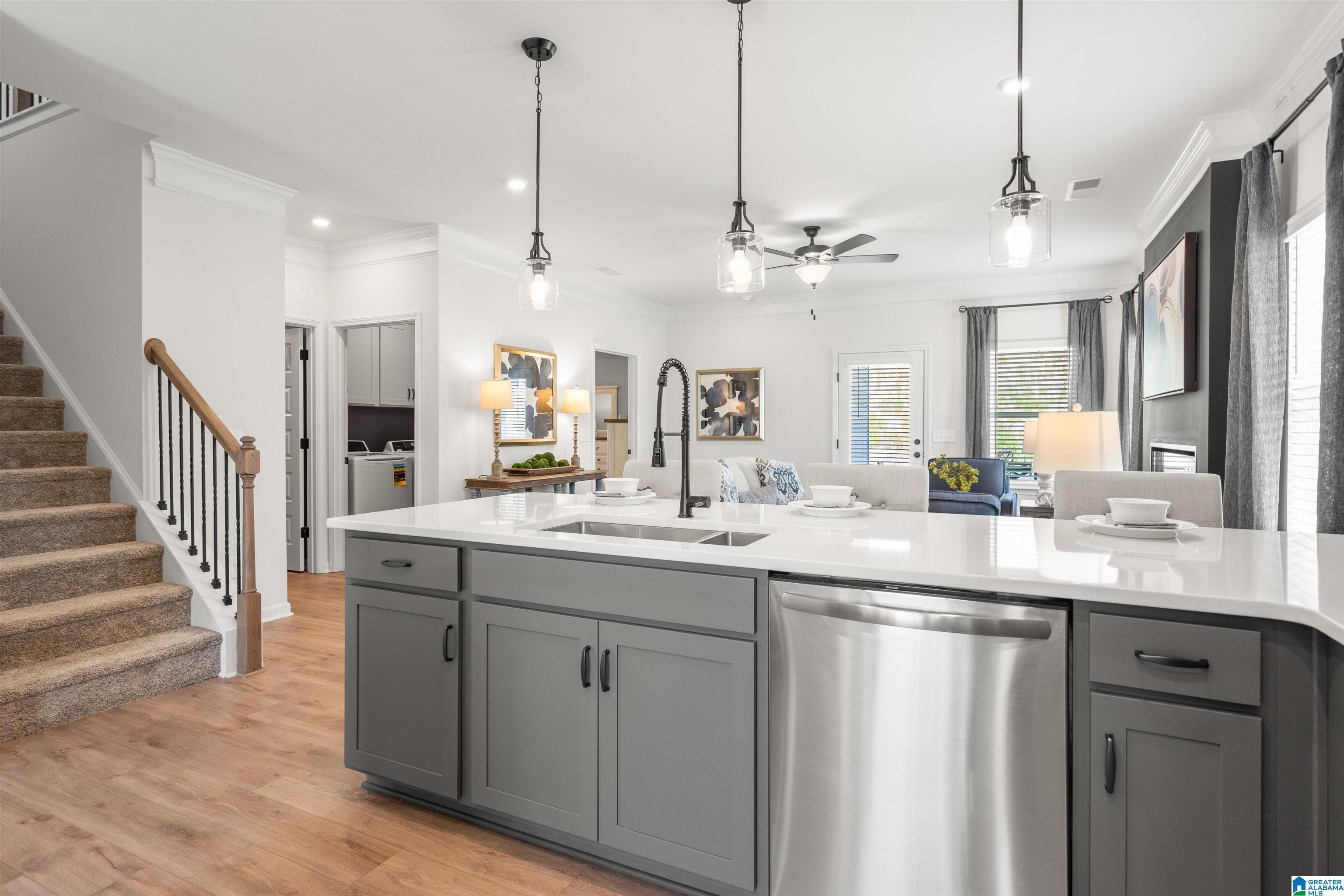 Kitchen island with white countertop, undermount sink, and integrated stainless steel dishwasher