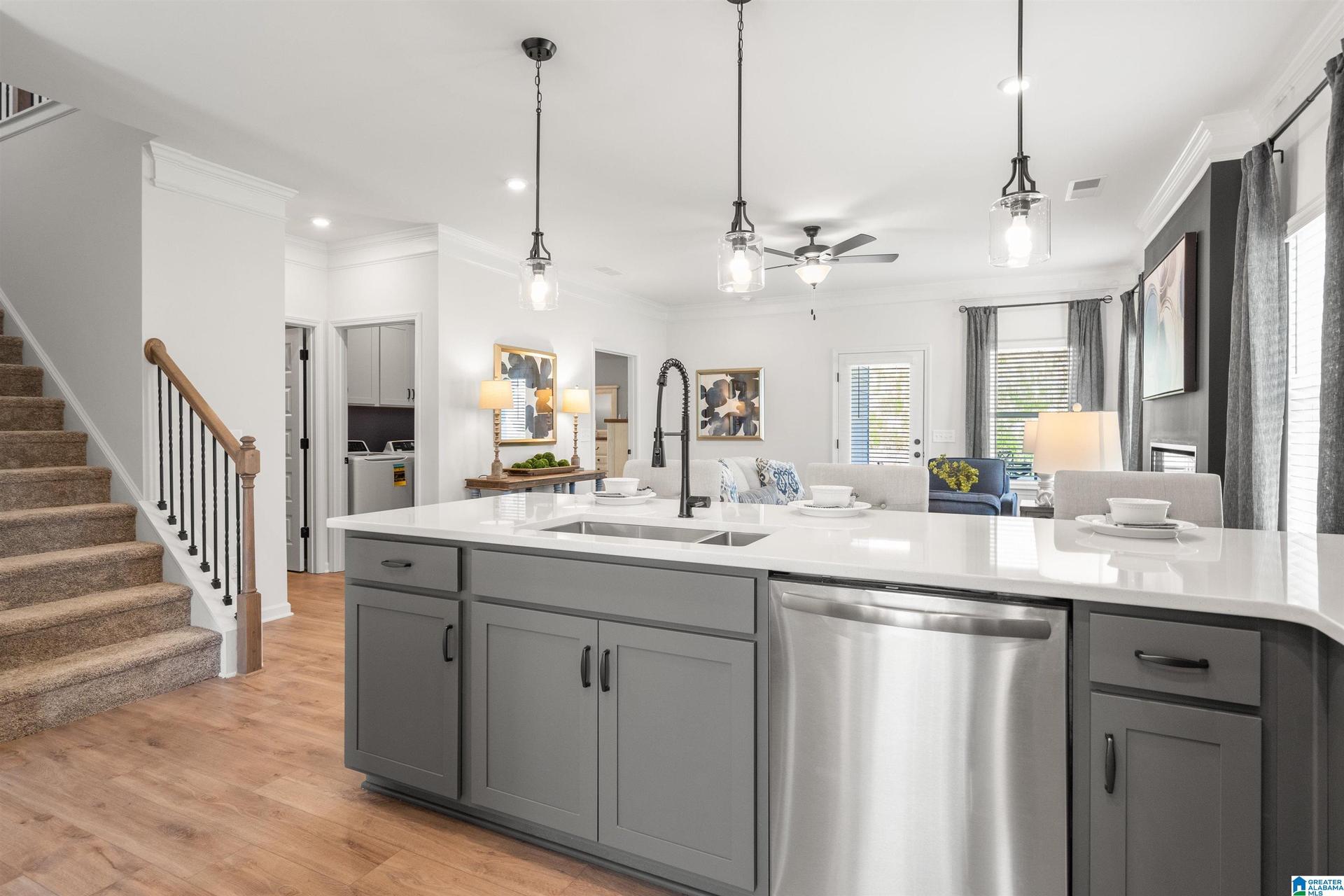 Kitchen island with white countertop, undermount sink, and integrated stainless steel dishwasher