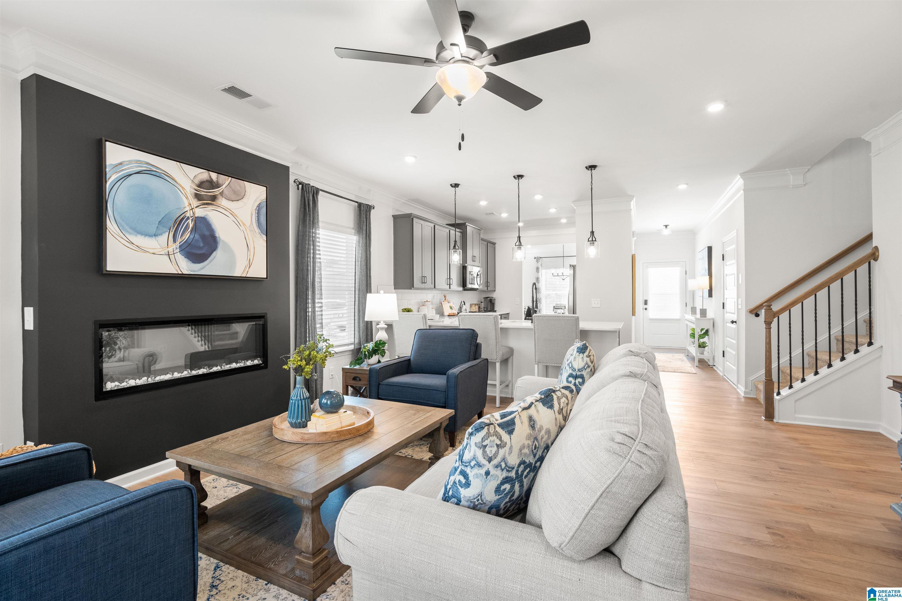 Open-concept living area with a built-in linear electric fireplace, wood-finish flooring, and crown molding