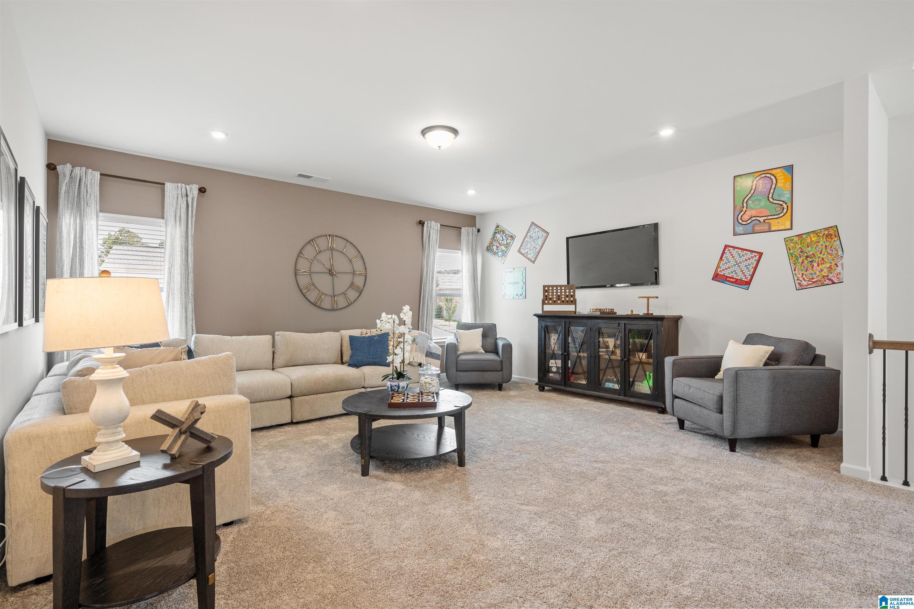 Carpeted living area with recessed lighting, multiple windows, and a built-in media console