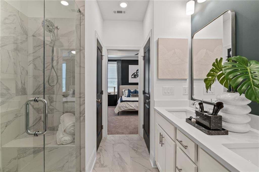 Owner's suite includes a private ensuite bath with sleek cabinetry and refined finishes. *Photos are not the actual unit, but of the same floor plan and decorated model home.