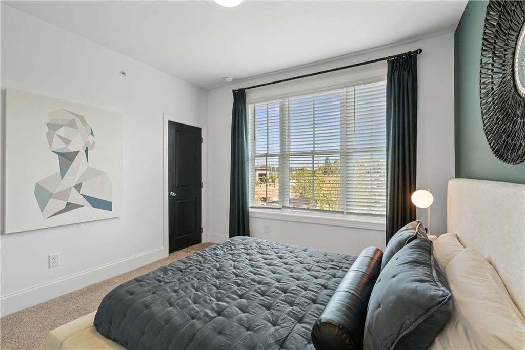 Secondary bedroom with neutral tones, carpeted flooring, and a large window providing natural light. Spacious walk-in closet attached. *Photos are not the actual unit, but of the same floor plan and decorated model home....