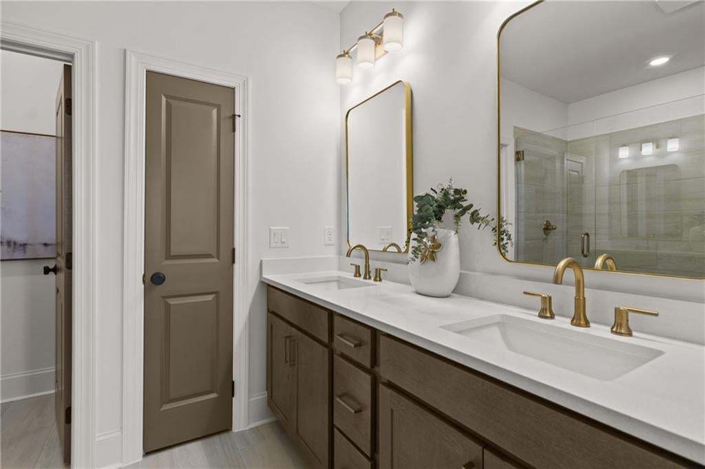 Owner bathroom with dual vanity, quartz countertops and upgraded gold design package. *Photos are not the actual unit. Decorated model home photos used.