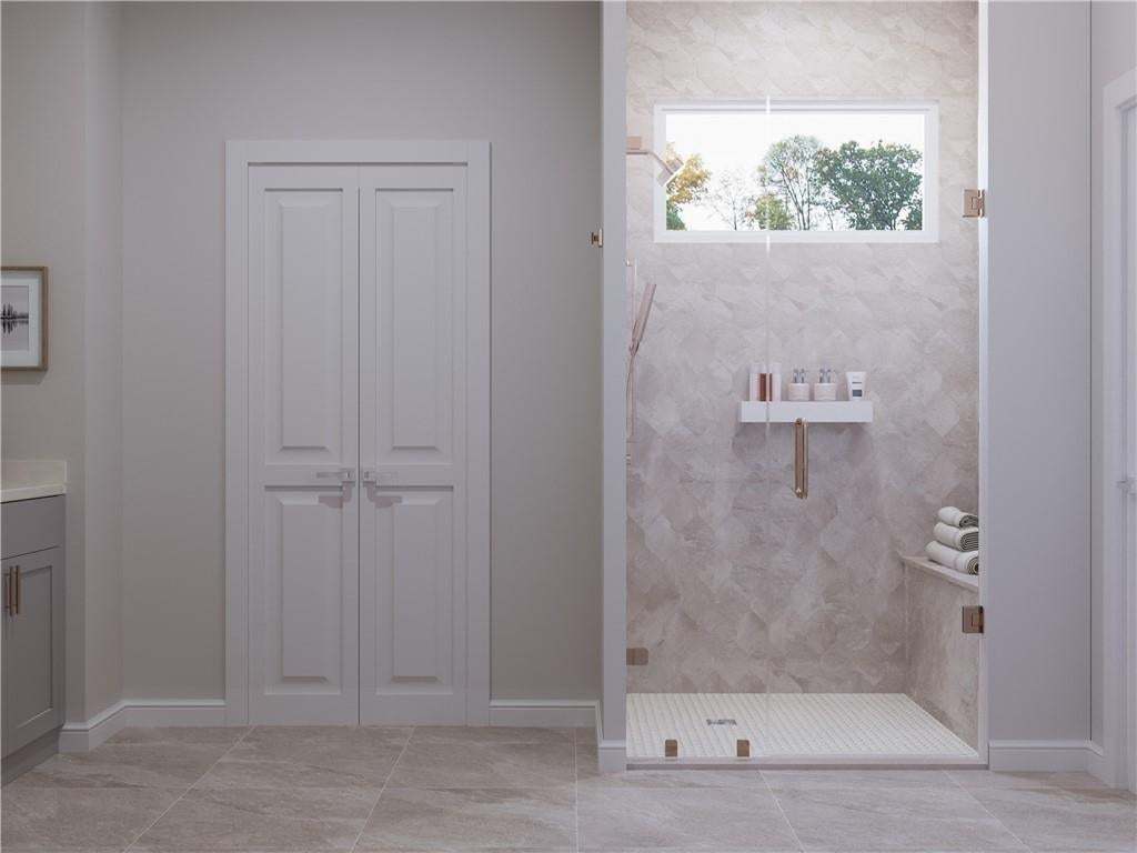 Primary bathroom with double doors and lovely shower with bench seating. Photo not of actual home but of a previously built TPG home.