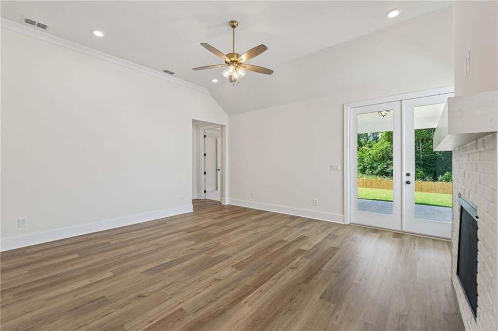 Spacious interior with vaulted ceilings, wood-finish flooring, recessed lighting, and a white brick fireplace
