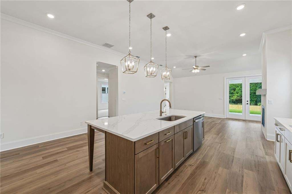 Gourmet kitchen island with a quartz countertop, integrated sink, bronze faucet, and pendant lighting