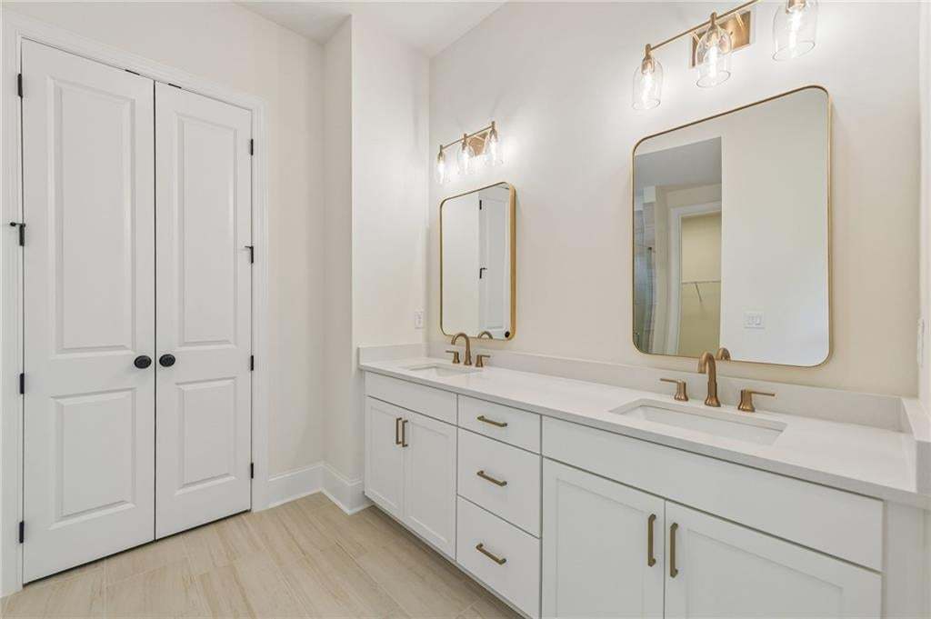 White dual vanity with integrated sinks, light-toned countertops, and brushed brass hardware