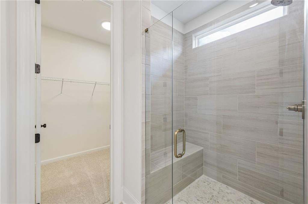 Walk-in shower with full-height tile surround, integrated bench, and frameless glass enclosure