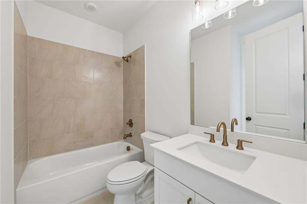 Contemporary bathroom featuring a white vanity with integrated sink and brushed bronze fixtures