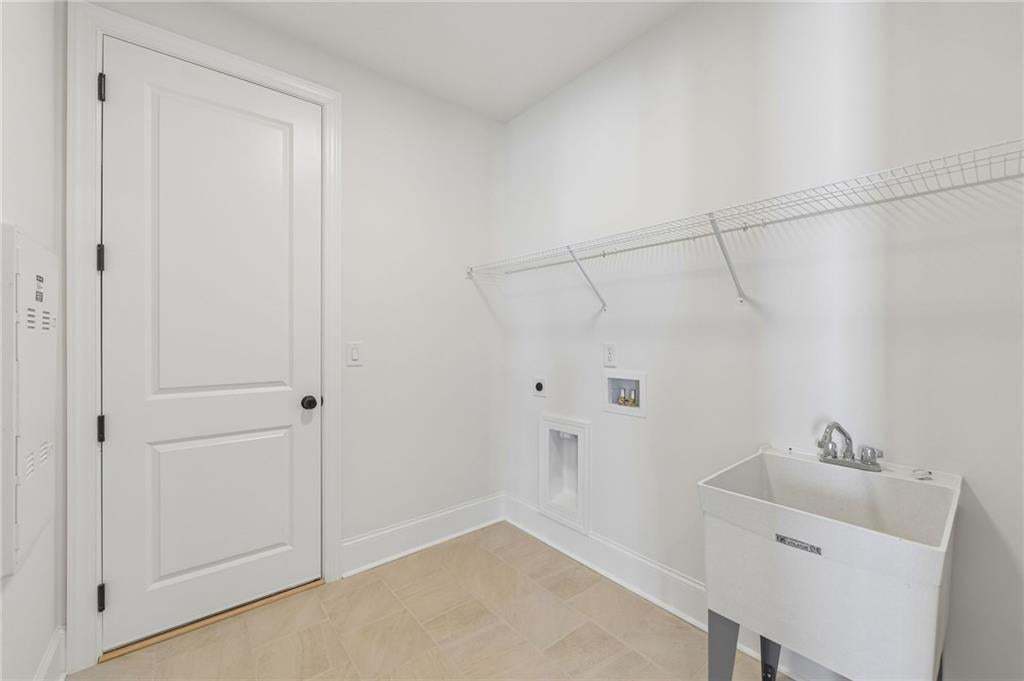 Dedicated laundry space featuring a utility sink, wire shelving, and tile flooring