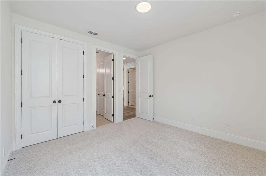 Spacious room featuring light-colored carpeting and crisp white walls