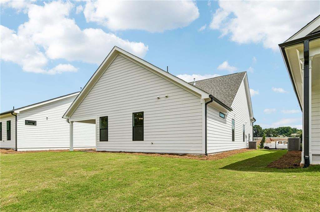 Rear exterior featuring white horizontal siding, black-framed windows, and dark-colored gutters