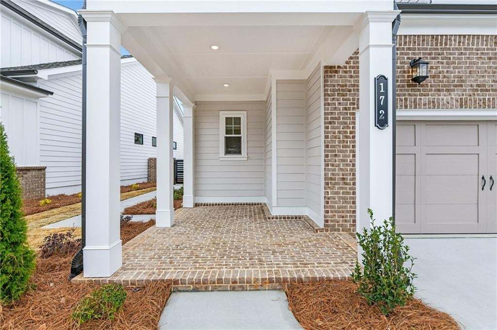 Entrance to property with covered porch, brick siding, and a garage