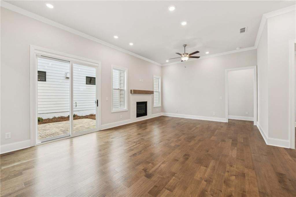 Unfurnished living room with a glass covered fireplace, recessed lighting, a ceiling fan, ornamental molding, and dark wood-style floors