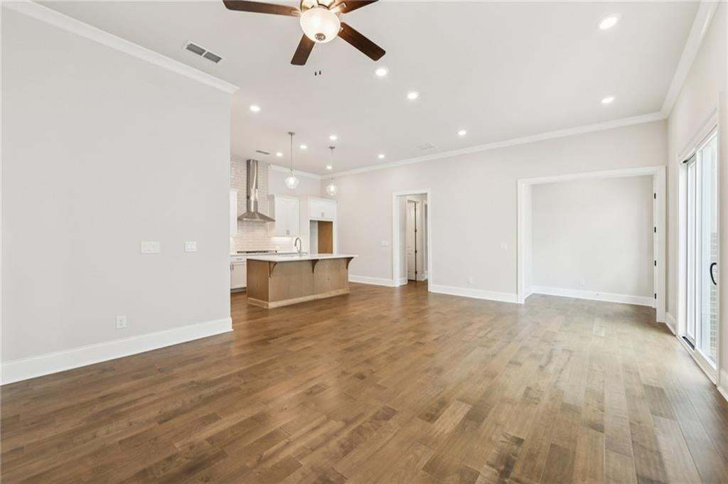 Unfurnished living room with ceiling fan, recessed lighting, dark wood finished floors, and ornamental molding