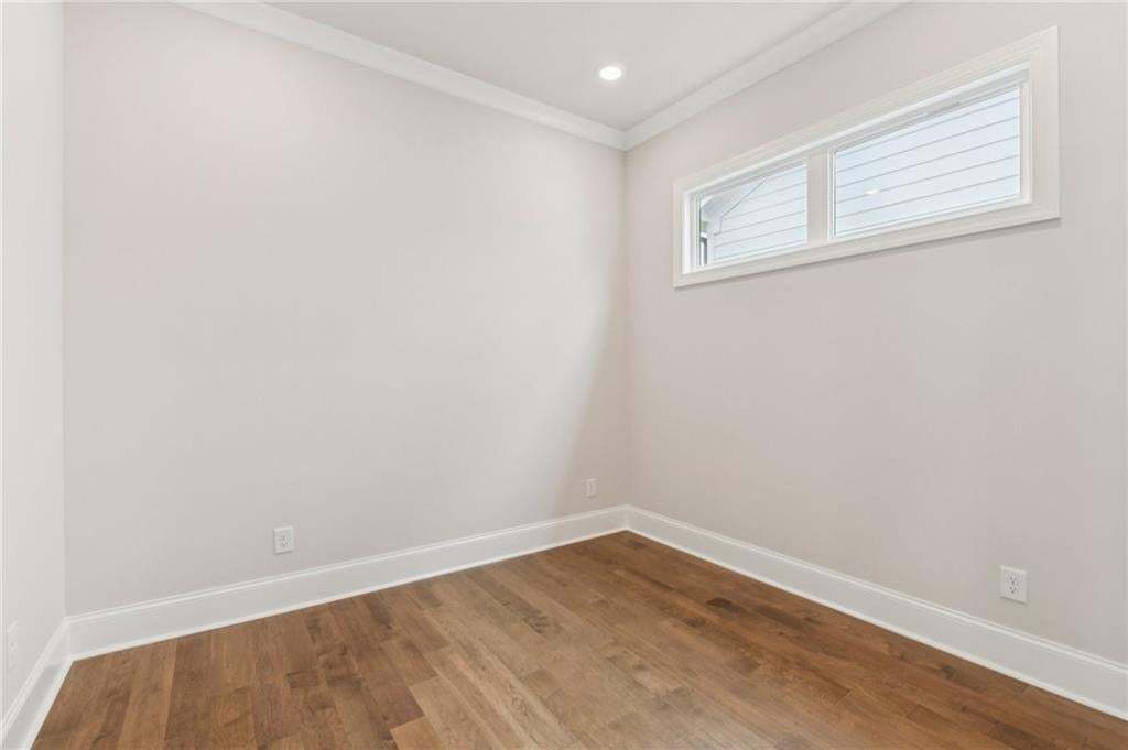 Empty room with crown molding, wood finished floors, and recessed lighting