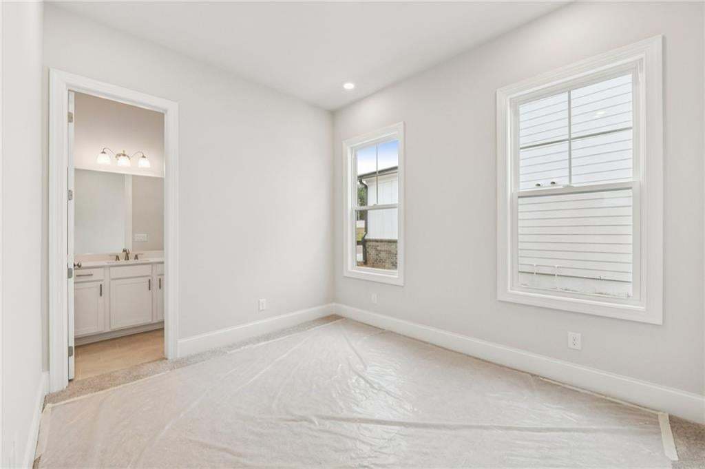 Unfurnished bedroom with light carpet and ensuite bathroom