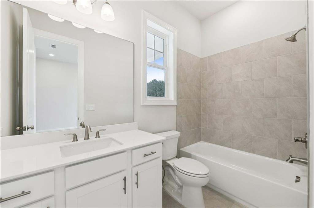 Bathroom with shower / bathtub combination, vanity, and light tile patterned flooring