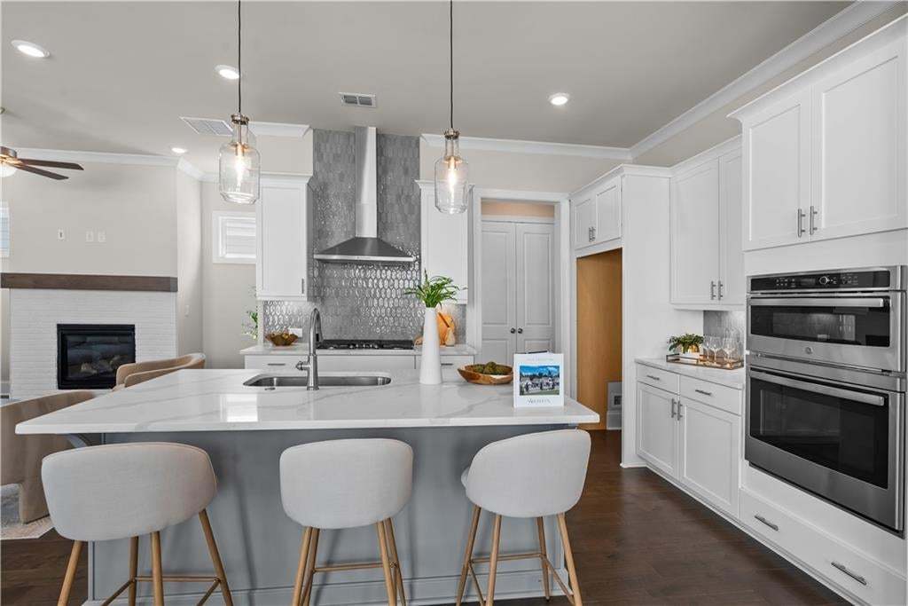 Contemporary kitchen with a large central island featuring a white-veined countertop and pendant lighting