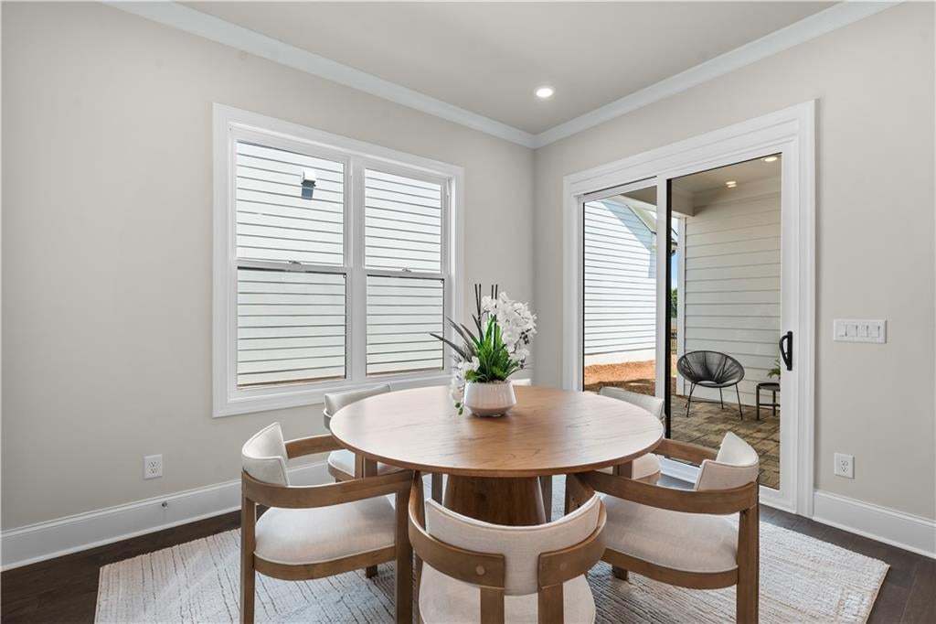 Dining area featuring dark wood-finish flooring, light grey walls, and white crown molding