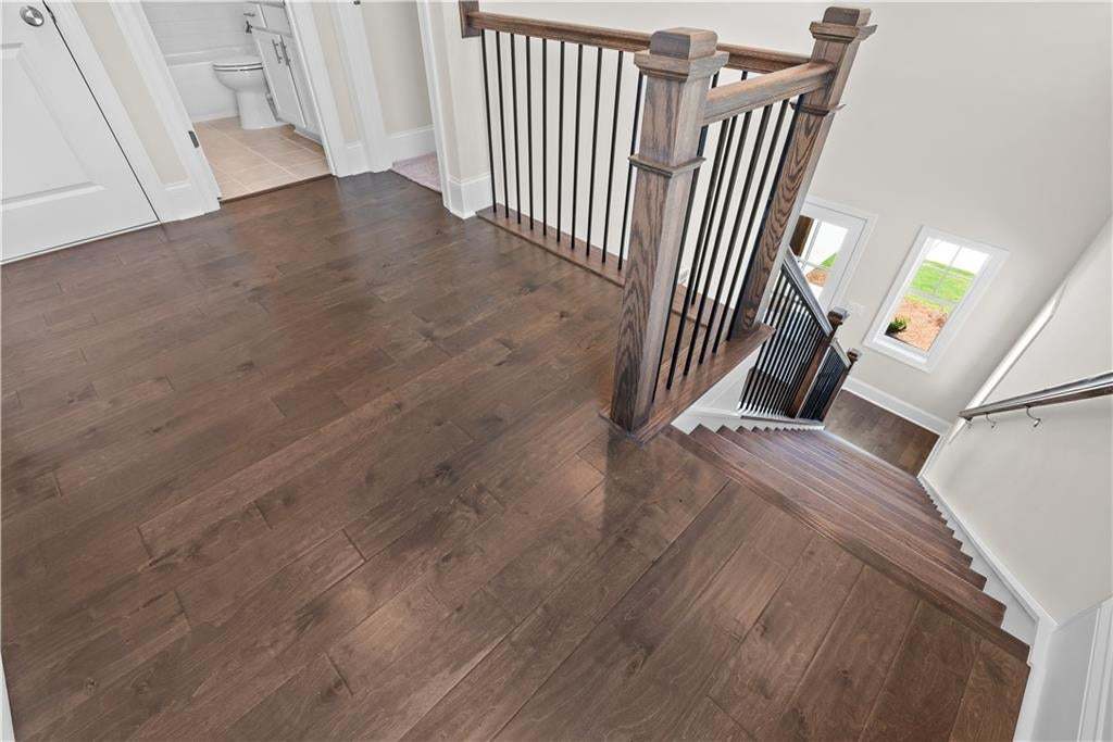 Wood-finish flooring throughout, complemented by a staircase featuring dark wood newel posts and handrails with black metal balusters