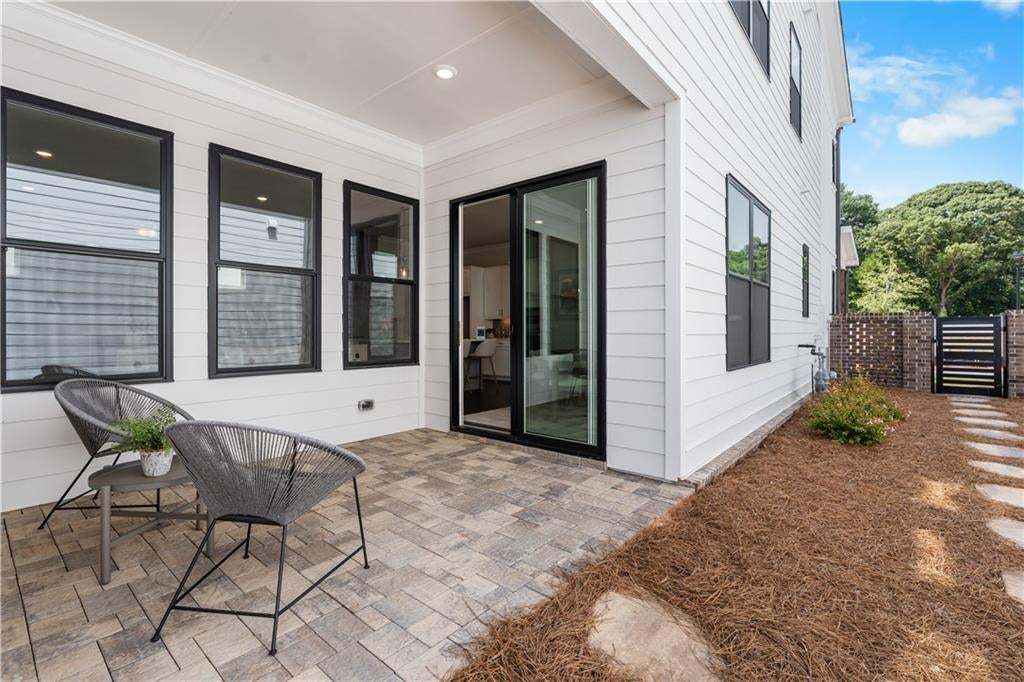 Covered patio with paver flooring, white siding, and black-framed windows