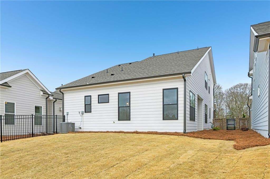 Back of house with roof with shingles and a fenced backyard