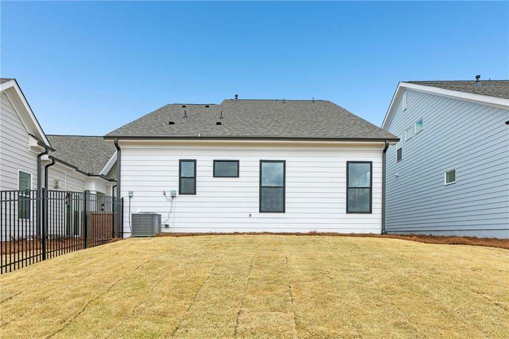 Back of house with a shingled roof and a lawn