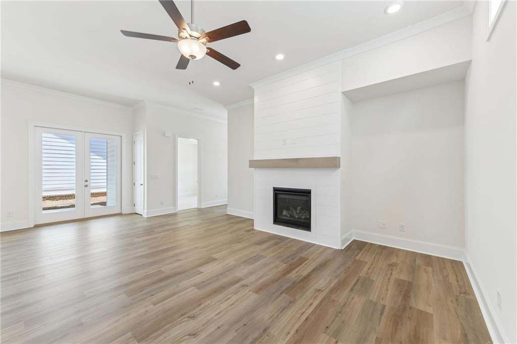 Spacious living area featuring wood-finish flooring, a shiplap-accented fireplace with a wood mantel, and an integrated media niche