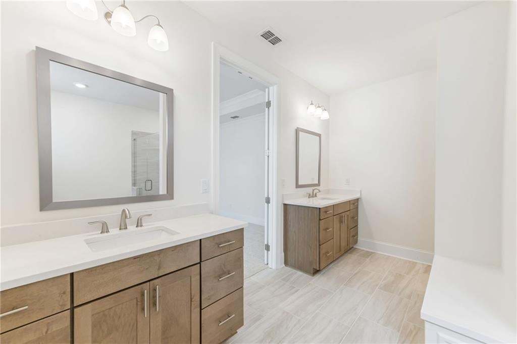 Dual vanity bathroom featuring light wood-finish cabinetry, white countertops, and brushed nickel fixtures
