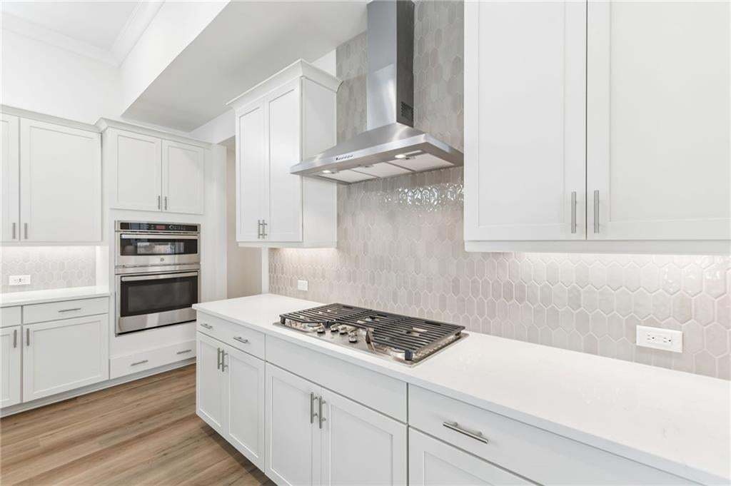 Modern kitchen featuring white shaker cabinetry, stainless steel appliances, a gas cooktop, white countertops, and a hexagonal tile backsplash