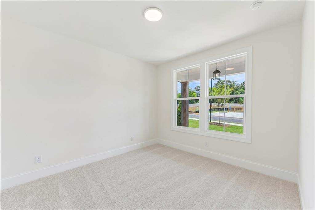 Bright room featuring dual windows, light-toned carpeting, white walls, clean baseboards, and a flush-mount ceiling light