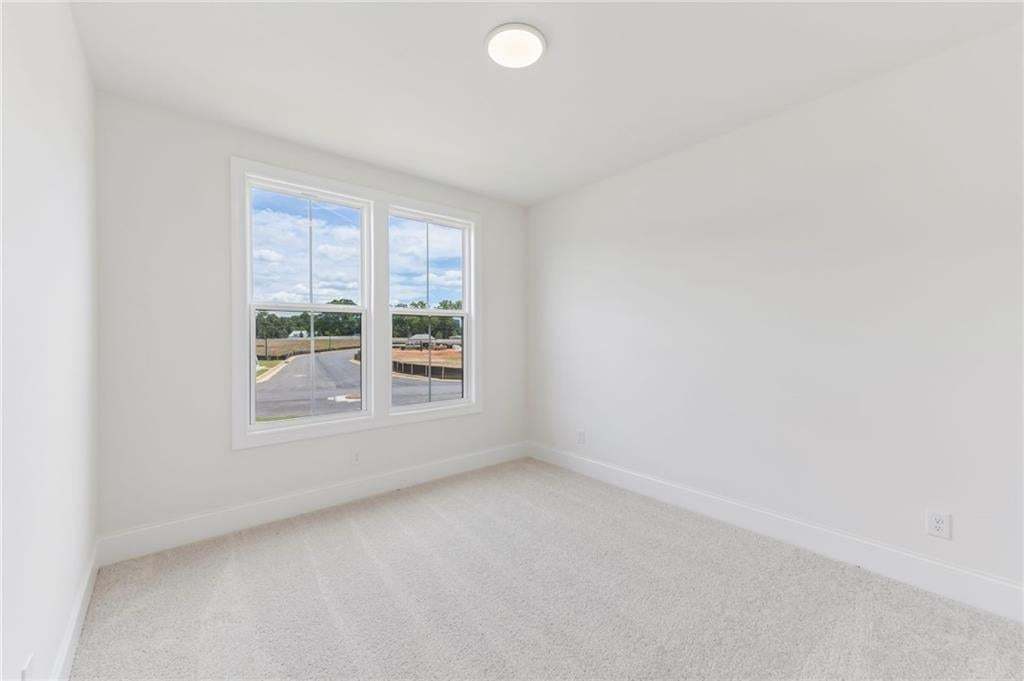 Bright room featuring two large windows, white walls, light-colored carpet, white baseboards, and a flush-mount ceiling light fixture
