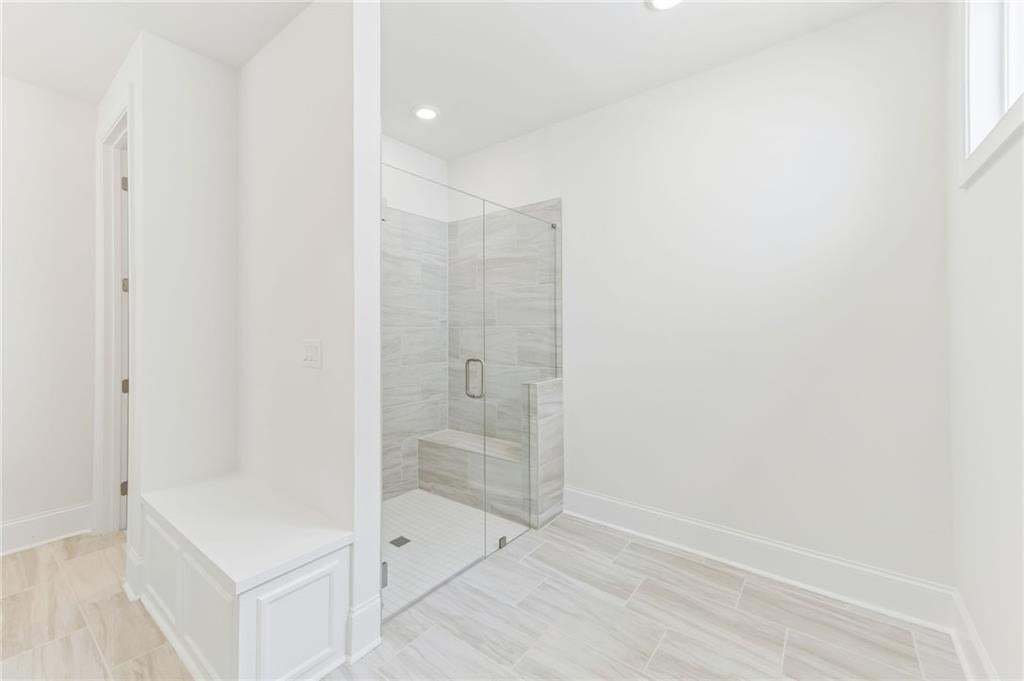 Walk-in shower with clear glass enclosure, integrated bench, and tiled walls