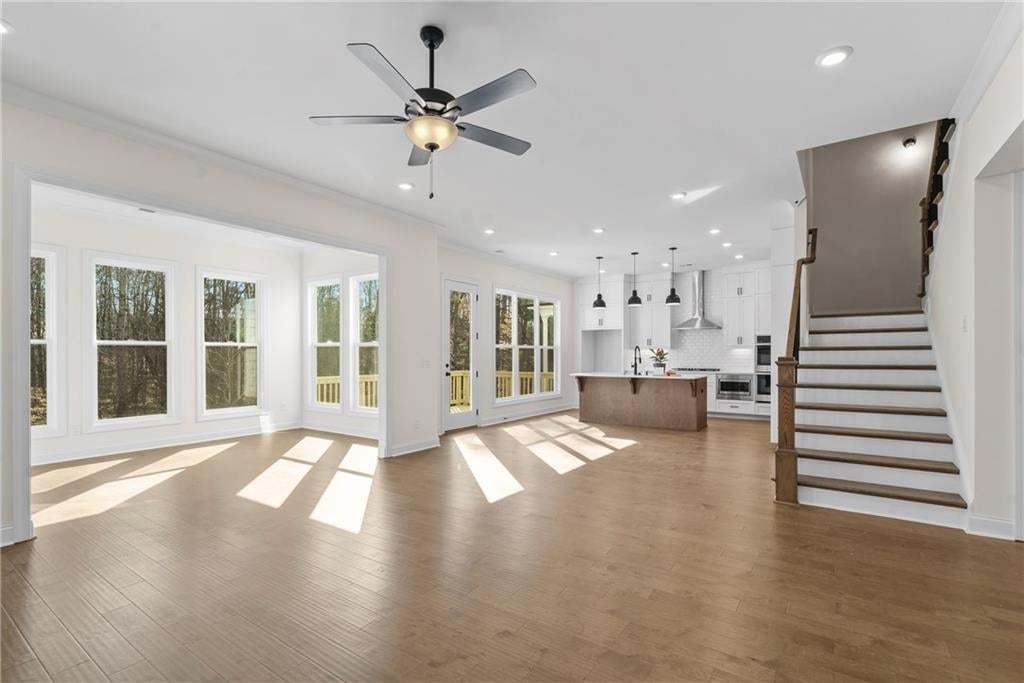 Living area featuring a fireplace with a shiplap accent wall and wood mantel, wood-finish flooring, recessed lighting, and a ceiling fan