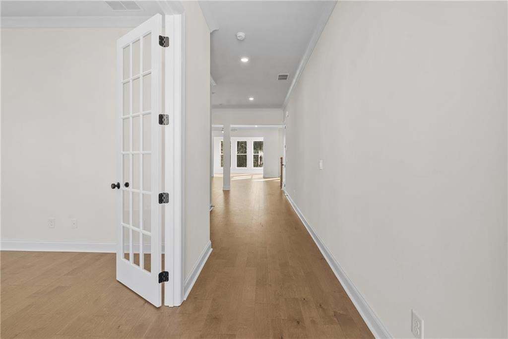 Spacious living area featuring light wood-finish flooring, a contemporary ceiling fan, and recessed lighting