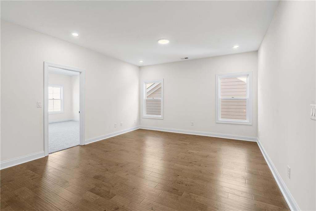 Expansive room featuring wood-finish flooring, white walls, and bright overhead lighting