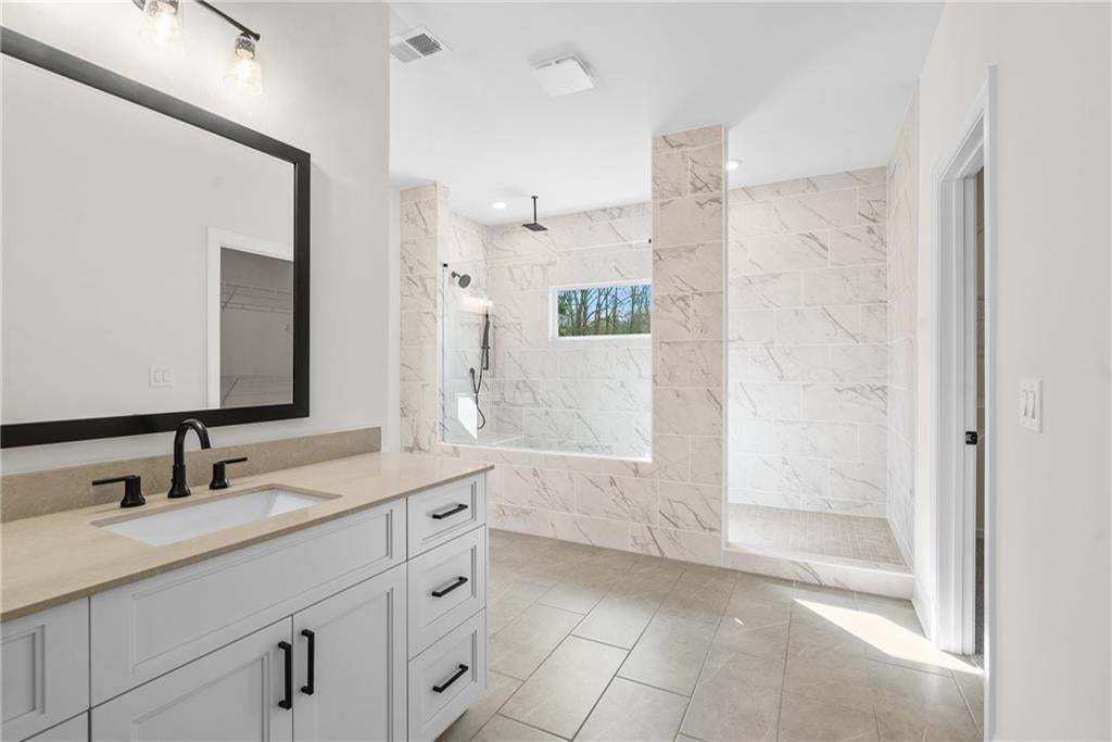Contemporary bathroom featuring a spacious walk-in shower with tile surround, a built-in bathtub, and a double vanity with a light-colored countertop
