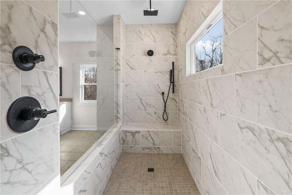 Walk-in shower featuring large format veined wall tiles, built-in bench, and a rectangular window