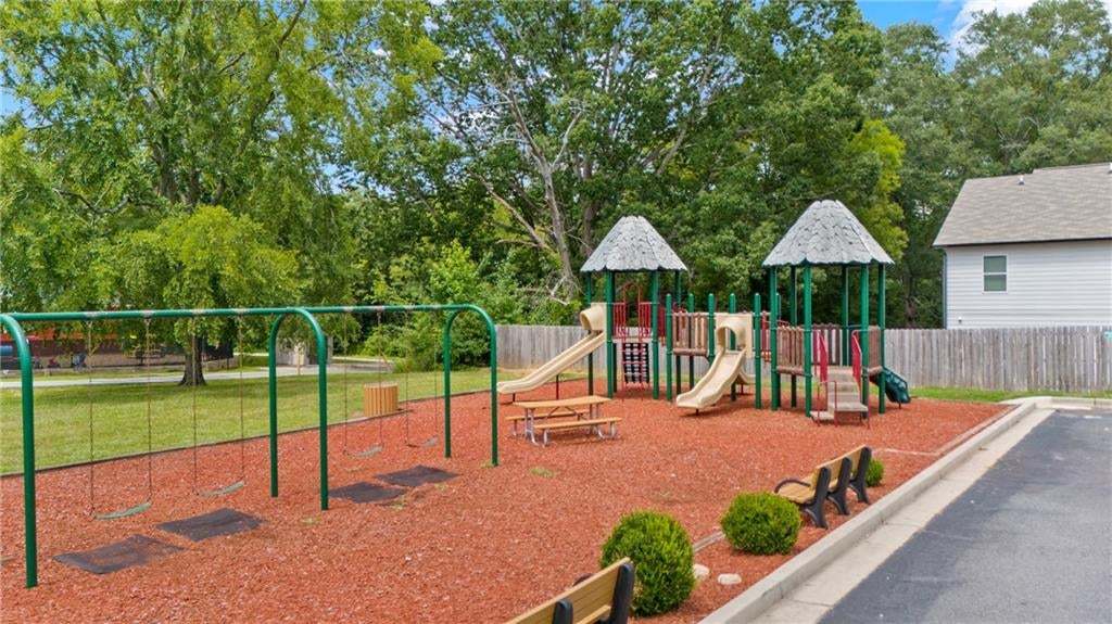 Community playground featuring a swing set, multi-level play structure with slides, and picnic table